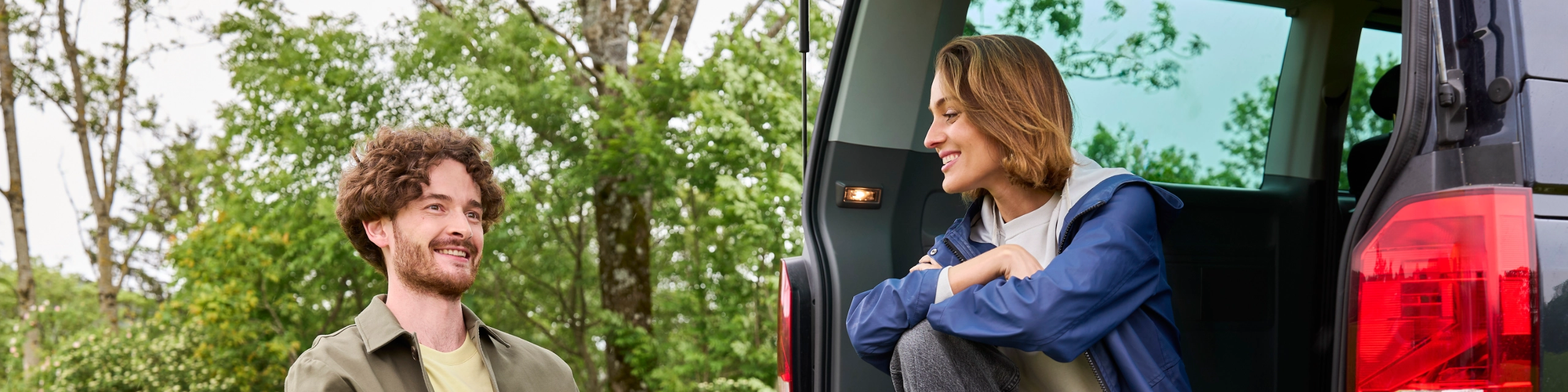 Ein Paar sitzt entspannt beim Auto – Symbol für Sicherheit durch die Leasingratenversicherung.