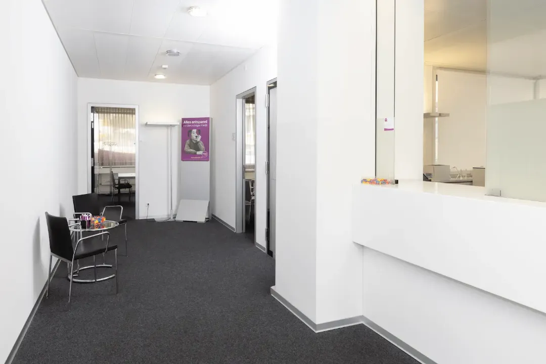 Counter area of the BANK-now Zurich-Oerlikon branch with bright interior and poster in the background.