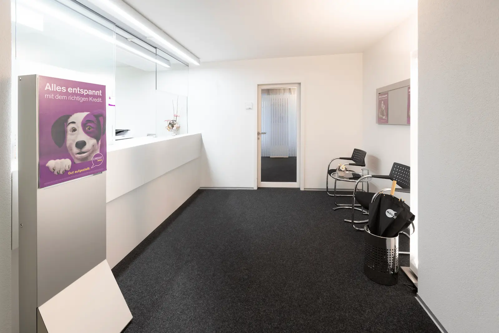 Wartebereich der BANK-now Filiale Bern mit Sitzgelegenheiten und Poster.