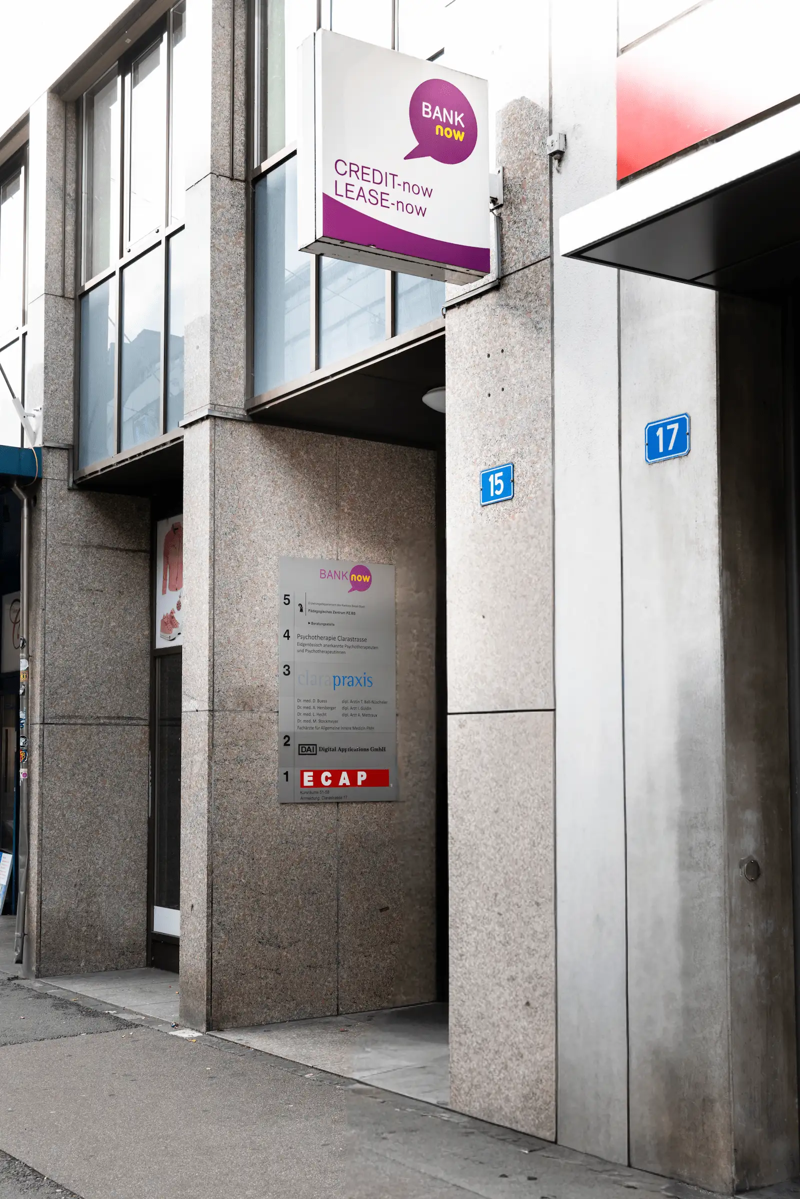 Zweiter Blick auf den Eingang der BANK-now Filiale Basel mit Schildern und Hausnummern.