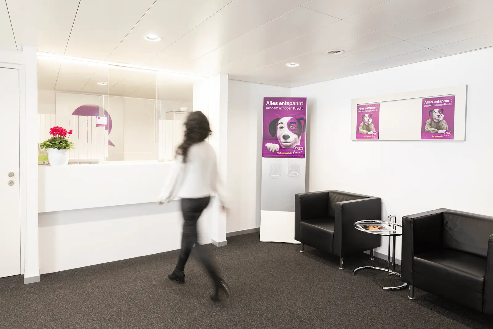 Heller Schalterbereich der BANK-now Filiale Basel mit Empfangstheke und Sitzgelegenheiten.