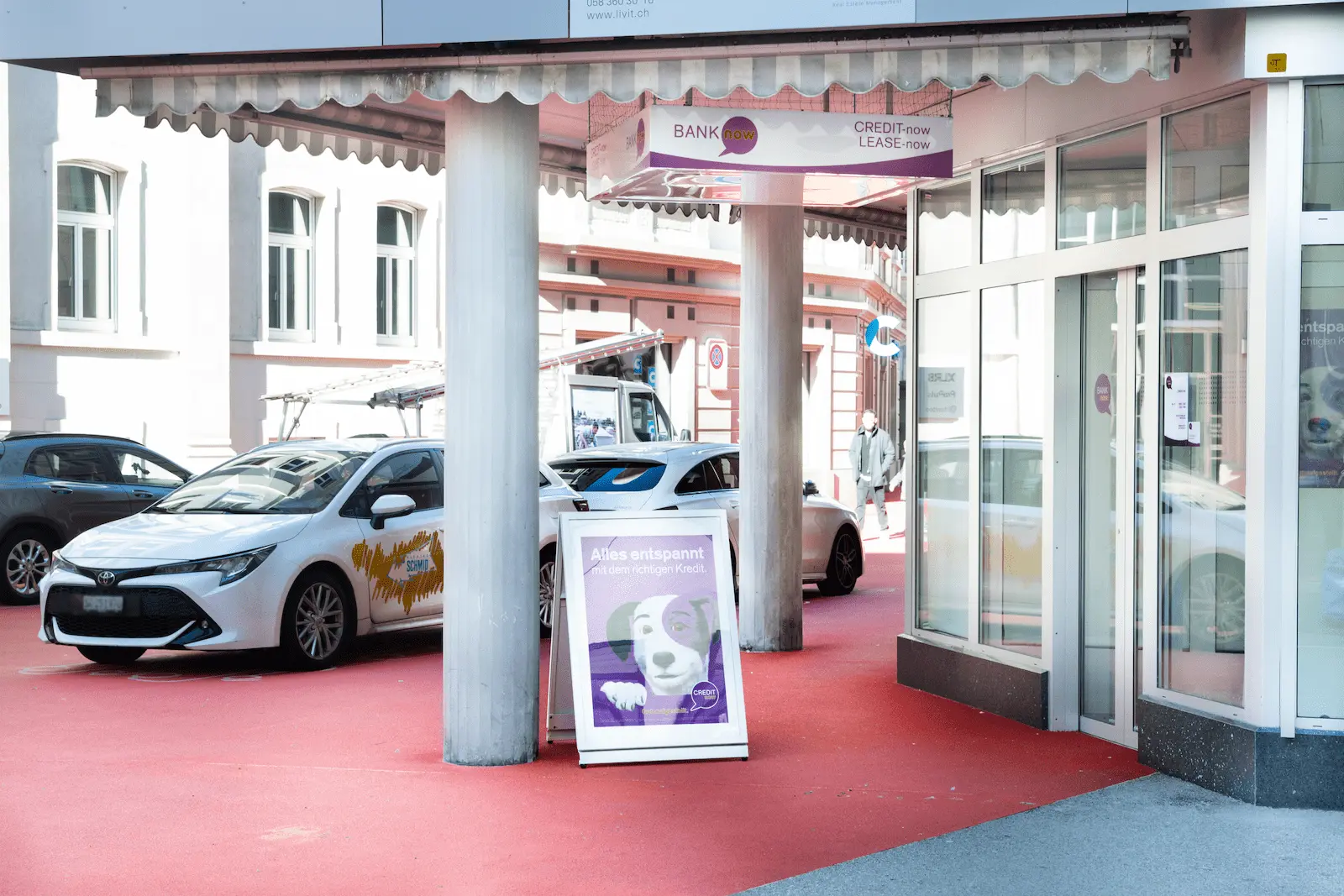 Besprechungsraum der BANK-now Filiale St. Gallen mit Tisch, Stühlen und Wandpostern.